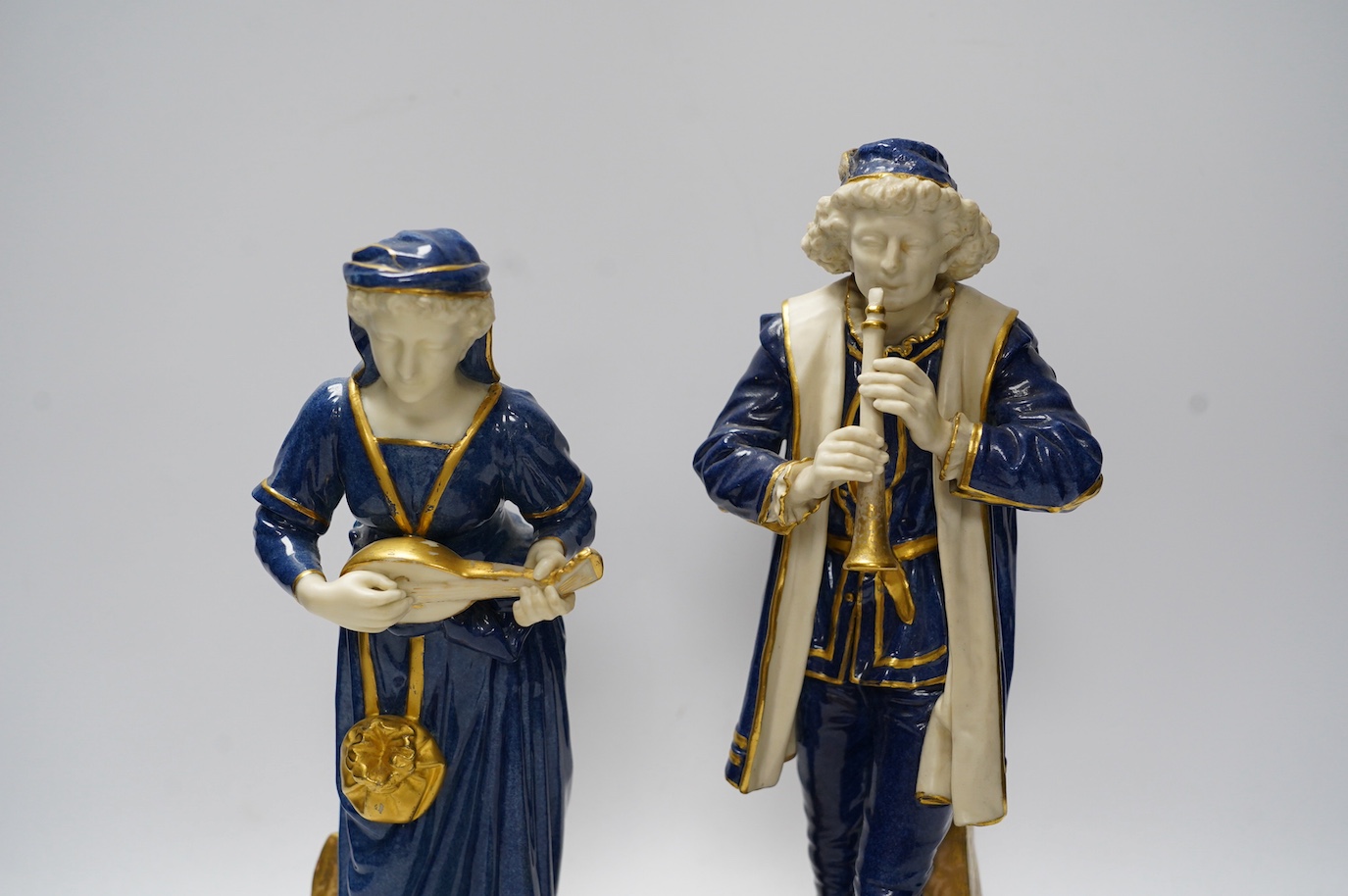 A pair of Worcester 'musician' figures by Hadley, 143 and 126, 30cm. Condition - some wear to gilding